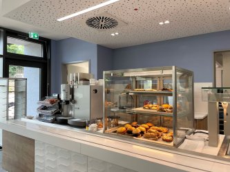 In der Kantine des Landratsamtes liegen belegte Brötchen aus. Man sieht eine Kaffeemaschine und kleine Snacks.