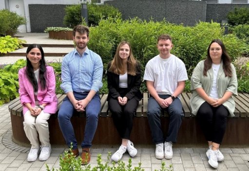 Fünf junge Menschen sitzen auf einer Bank im Innenhof des Landratsamtes in Bad Hersfeld. Im Hintergrund sieht man grüne Pflanzen. 