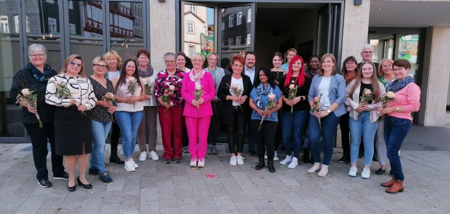 Viele Frauen und einige Männer stehen vor dem Bad Hersfelder News-Café. Die geehrten Mitarbeitenden der Kreisaltenpflege Hersfeld-Rotenburg halten jeweils eine Rose in der Hand. Alle lächeln.