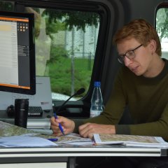 Ein Mann sitzt im Einsatzleitwagen und notiert etwas auf einer Karte.