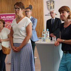 Personen stehen im KT-Saal der Kreisverwaltung und hören einem Vortrag zu.