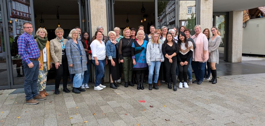 Mehrere Personen stehen vor dem News-Café in der Bad Hersfelder Innenstadt. Sie schauen in die Kamera. Der Boden ist feucht.