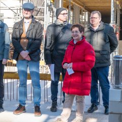 Bürgermeisterin Anke Hofmann steht vor der Baustelle und spricht mit mehreren Personen. Im Hintergrund ist das Baugerüst zu sehen.